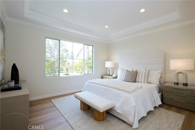 bedroom with light wood-style flooring, recessed lighting, baseboards, a tray ceiling, and crown molding