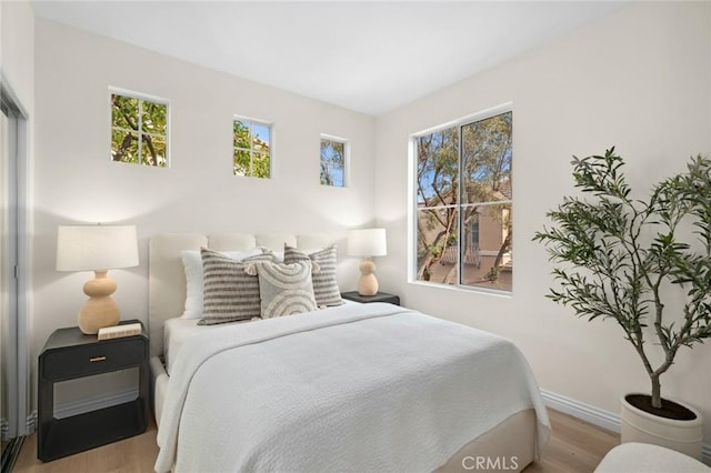 bedroom featuring light wood finished floors and baseboards