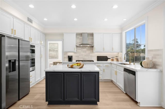 kitchen featuring stainless steel appliances, a sink, light countertops, a center island, and wall chimney exhaust hood