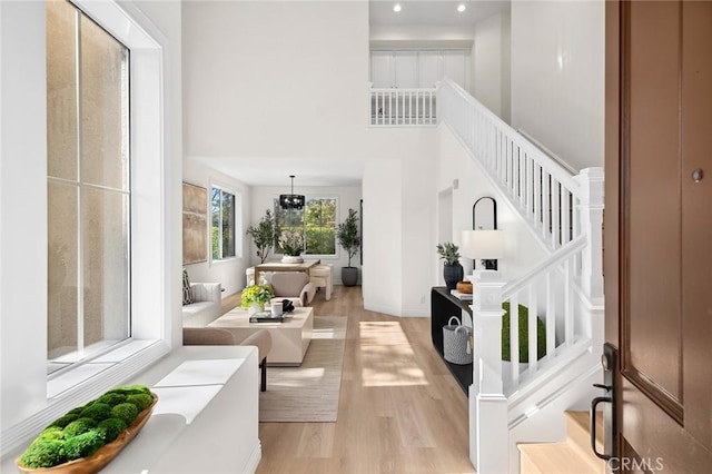 foyer featuring a towering ceiling, baseboards, stairway, and light wood finished floors