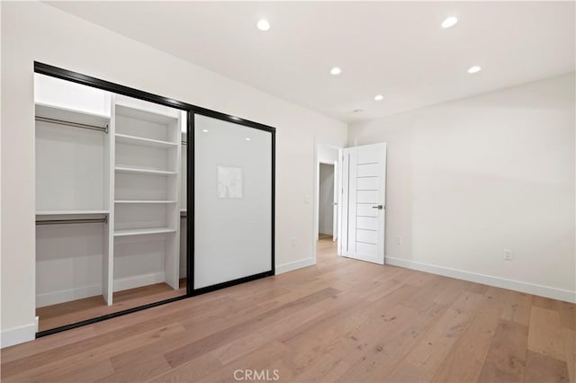 unfurnished bedroom featuring light wood-type flooring and a closet