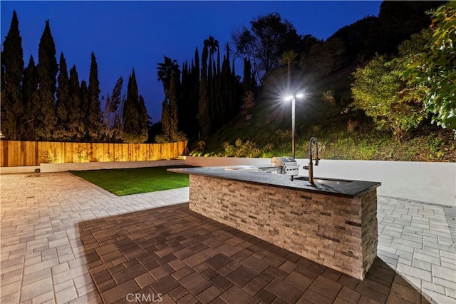 patio at twilight featuring area for grilling, a grill, and sink