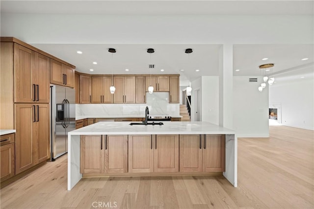 kitchen with a spacious island, pendant lighting, sink, and stainless steel fridge with ice dispenser