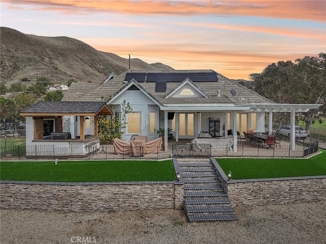 back of property featuring french doors, roof mounted solar panels, a patio area, a pergola, and fence private yard