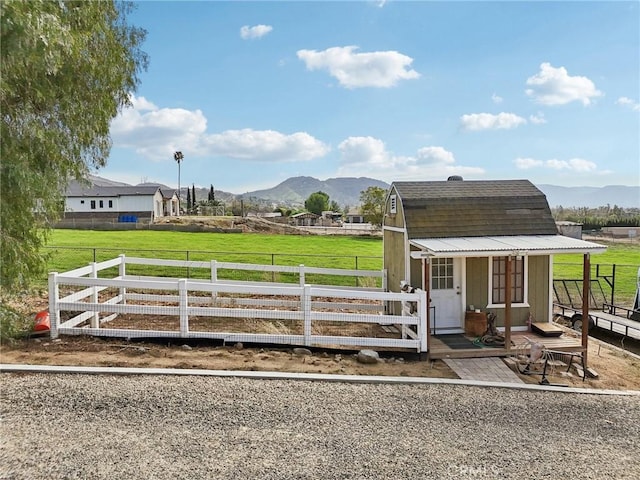 4210 Crestview Dr, Norco, CA 92860 - view of front facade with a fenced backyard, a mountain view, a gambrel roof, and an outbuilding