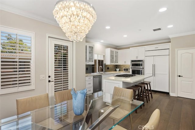 dining space with a chandelier, recessed lighting, dark wood-type flooring, visible vents, and ornamental molding