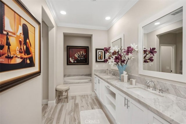 bathroom with a garden tub, crown molding, and a sink