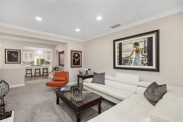 living area with visible vents, baseboards, crown molding, and recessed lighting