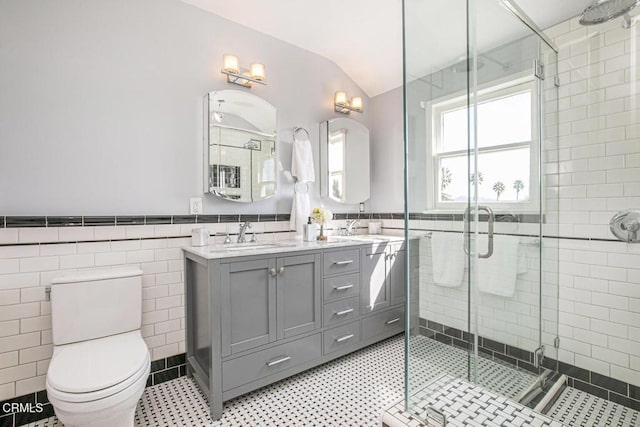 full bathroom featuring a stall shower, tile walls, a sink, and wainscoting