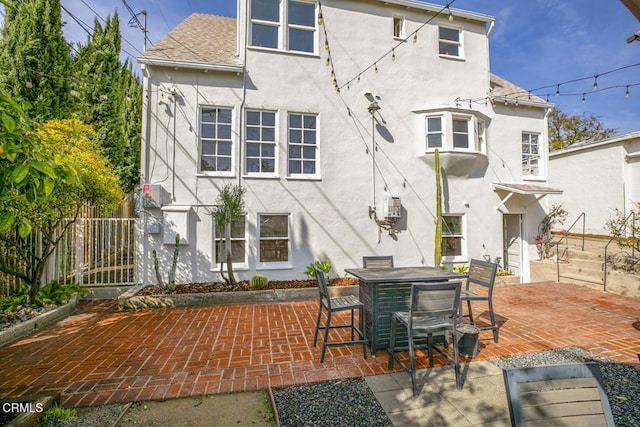 back of property featuring stucco siding, roof with shingles, fence, a patio area, and outdoor dining space