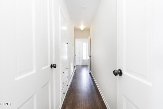 hallway featuring dark wood-style flooring and baseboards