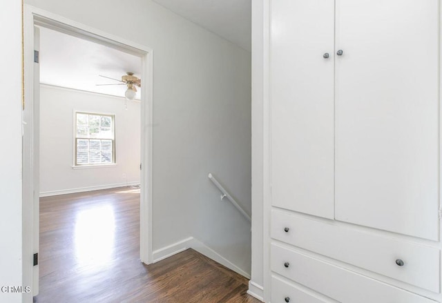 corridor featuring dark wood-style floors, baseboards, and an upstairs landing