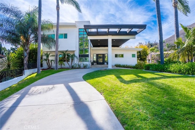 rear view of house featuring concrete driveway, a yard, and fence