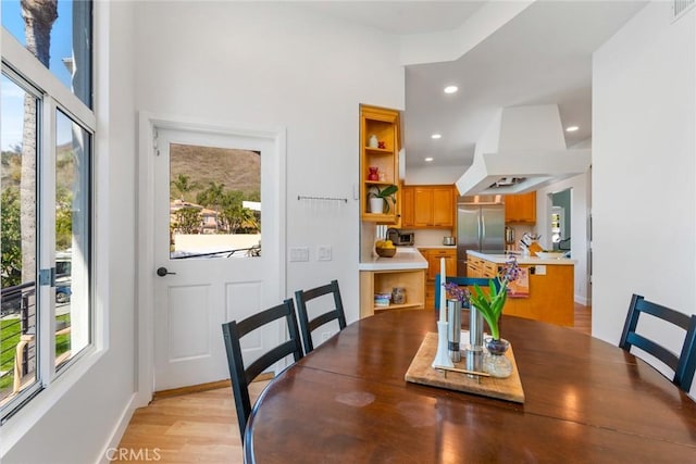 dining space with light wood finished floors, recessed lighting, a healthy amount of sunlight, and baseboards