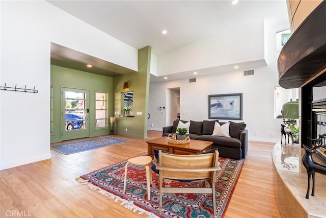 living room featuring recessed lighting, light wood-style floors, baseboards, and a towering ceiling