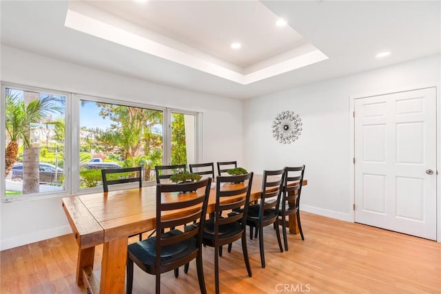 dining area with a tray ceiling, recessed lighting, baseboards, and light wood finished floors