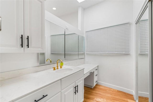 bathroom with vanity, recessed lighting, wood finished floors, and baseboards