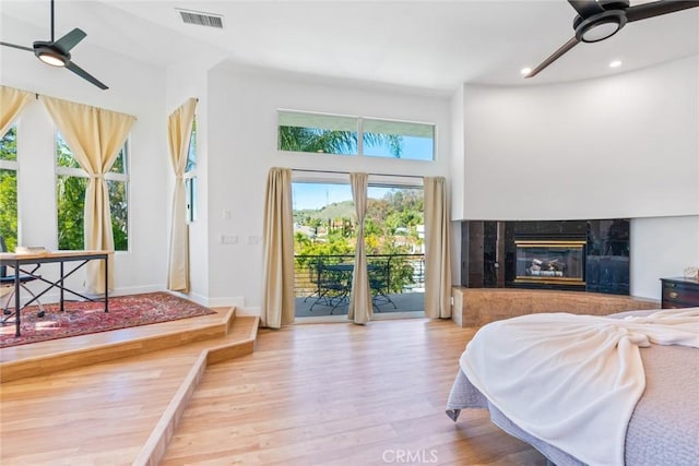 bedroom featuring visible vents, access to outside, wood finished floors, recessed lighting, and a fireplace