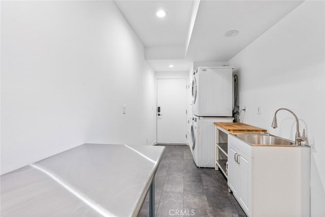 clothes washing area featuring a sink, stacked washer / drying machine, and recessed lighting