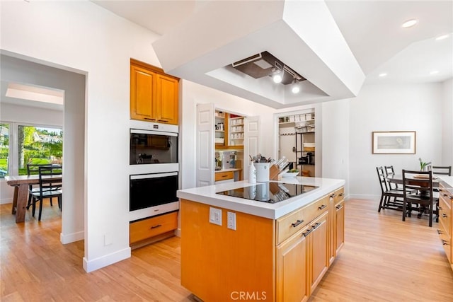 kitchen with light wood finished floors, double oven, light countertops, and black electric stovetop