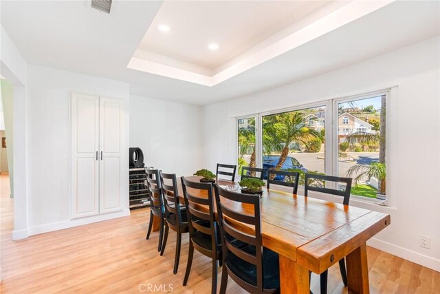 dining space with visible vents, baseboards, a tray ceiling, recessed lighting, and light wood-type flooring