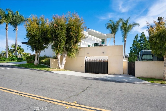 view of front of home with stucco siding, fence, and a gate