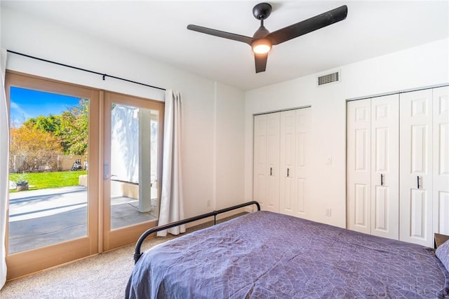 carpeted bedroom featuring visible vents, two closets, access to exterior, and a ceiling fan