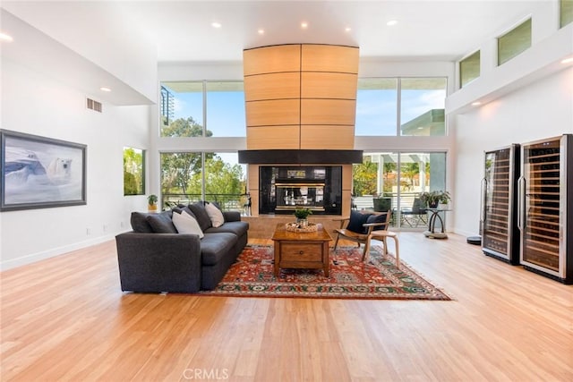 living room with visible vents, a healthy amount of sunlight, wine cooler, a multi sided fireplace, and wood finished floors