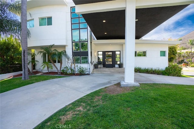 doorway to property with stucco siding, a yard, and french doors