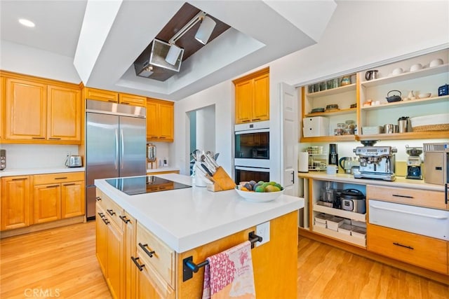 kitchen featuring a center island, light wood-style flooring, built in refrigerator, and black electric stovetop