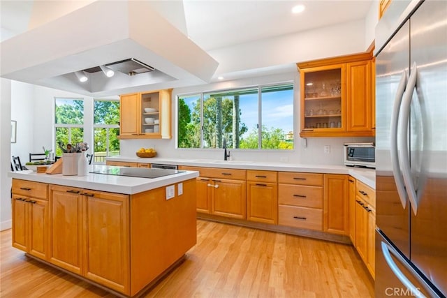 kitchen featuring light countertops, stainless steel fridge, light wood finished floors, and a sink