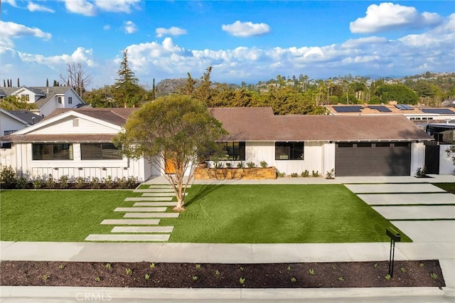 view of front of home featuring a garage, board and batten siding, concrete driveway, and a front yard