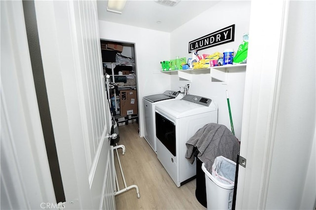 clothes washing area with washer and dryer and light hardwood / wood-style floors