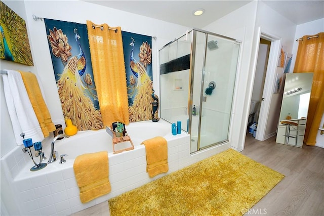 bathroom with hardwood / wood-style flooring, independent shower and bath, and toilet