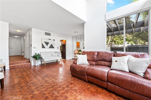 living area featuring a high ceiling and visible vents