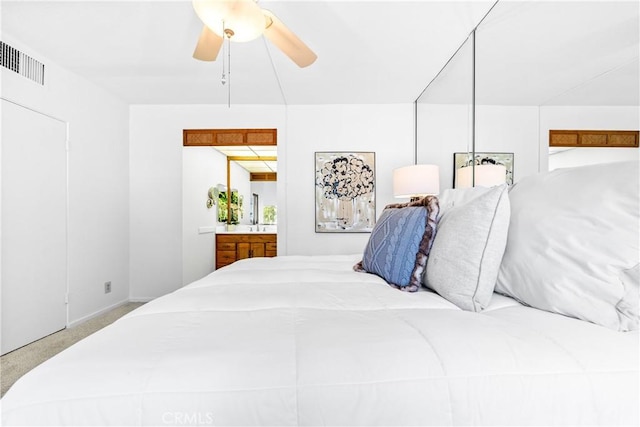 carpeted bedroom with visible vents, ensuite bath, and ceiling fan