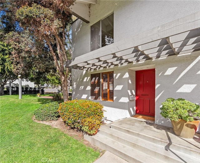 entrance to property featuring a yard, stucco siding, and a pergola