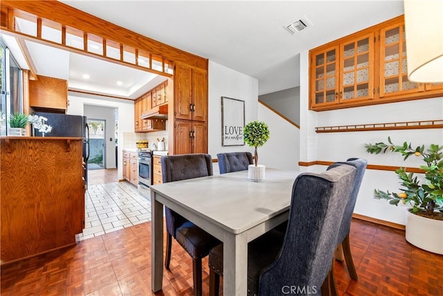 dining room with a tray ceiling, visible vents, and baseboards