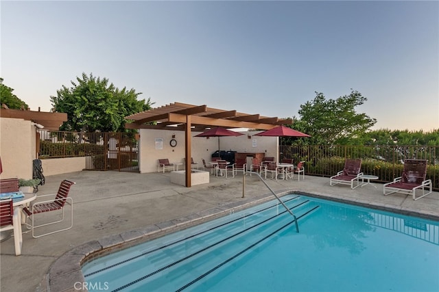 pool at dusk with a patio area and a pergola