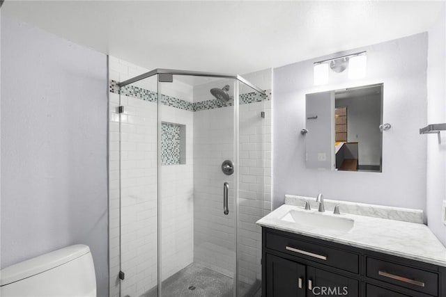 bathroom featuring vanity, a shower with shower door, and toilet