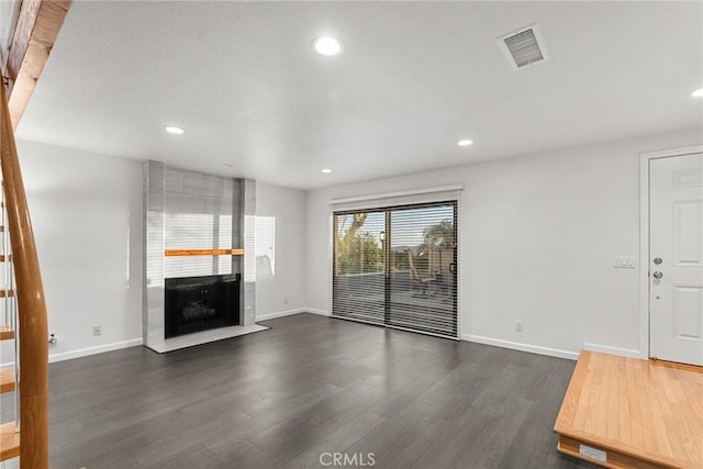 unfurnished living room with a large fireplace and dark hardwood / wood-style floors