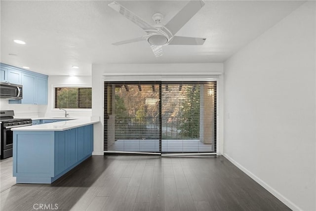 kitchen featuring kitchen peninsula, stainless steel appliances, dark hardwood / wood-style flooring, blue cabinets, and sink