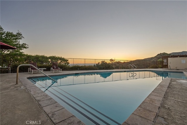 pool at dusk with a patio area and a mountain view