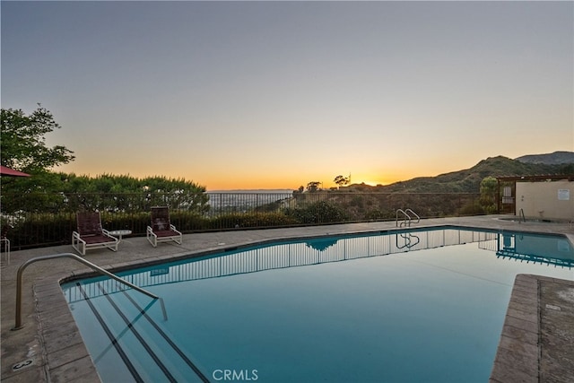 pool at dusk with a patio and a mountain view