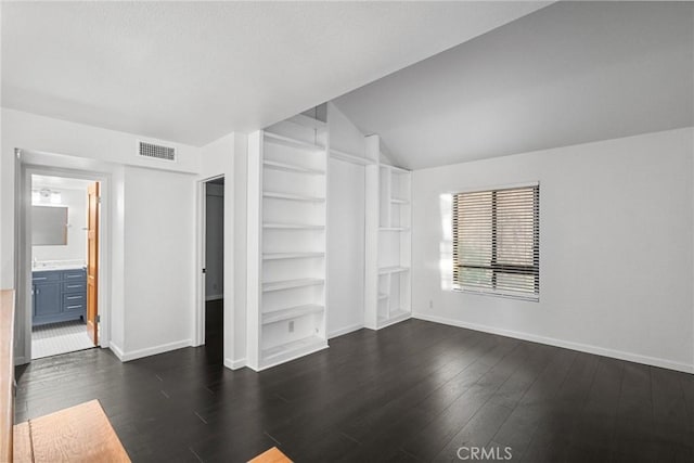 unfurnished bedroom with connected bathroom, vaulted ceiling, and dark hardwood / wood-style floors