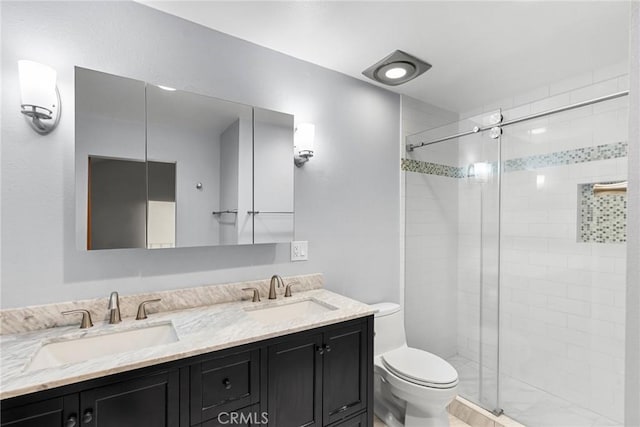 bathroom featuring a shower with shower door, vanity, and toilet