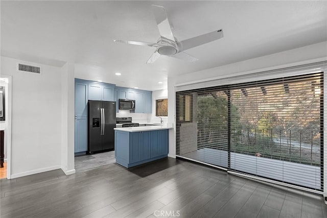 kitchen featuring appliances with stainless steel finishes, blue cabinetry, ceiling fan, dark hardwood / wood-style flooring, and kitchen peninsula