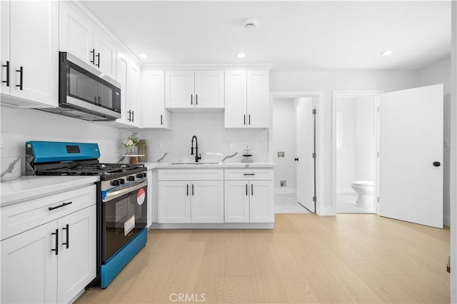 kitchen with light hardwood / wood-style flooring, sink, stainless steel appliances, and white cabinets