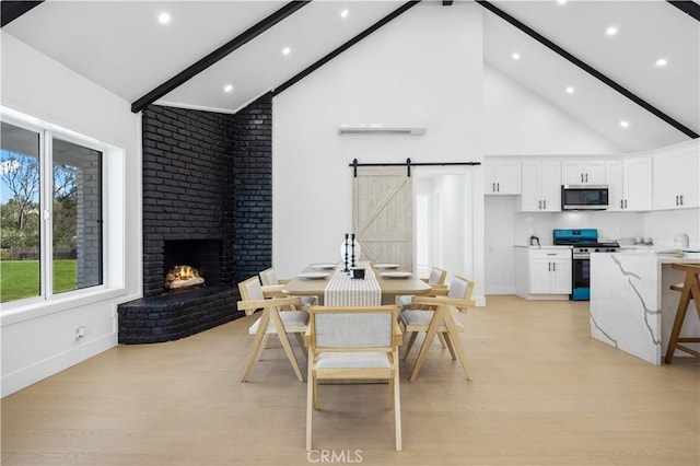 dining area featuring light hardwood / wood-style floors, high vaulted ceiling, a barn door, and beam ceiling