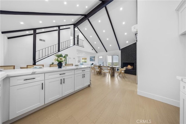 kitchen with a fireplace, white cabinets, light stone countertops, and light hardwood / wood-style flooring